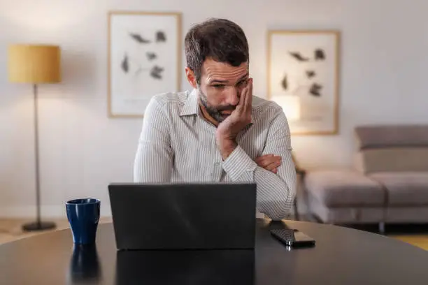 Frustrated business owner staring at laptop, trying to update their own website